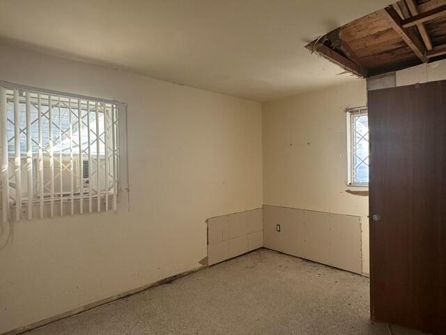 An unfinished bedroom features a damaged ceiling, exposed wall panels, and windows with security bars — 1781 NW 6th Terrace, Pompano Beach FL 33060, POMPANO BEACH, FL