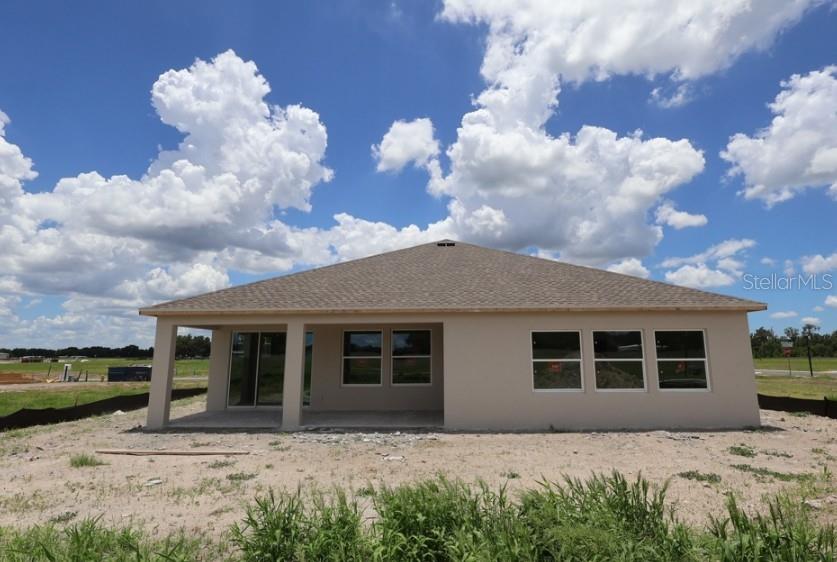 The exterior rear view of a single-story house features a covered patio and large windows — 314 STETSON RISE COURT, PLANT CITY, FL