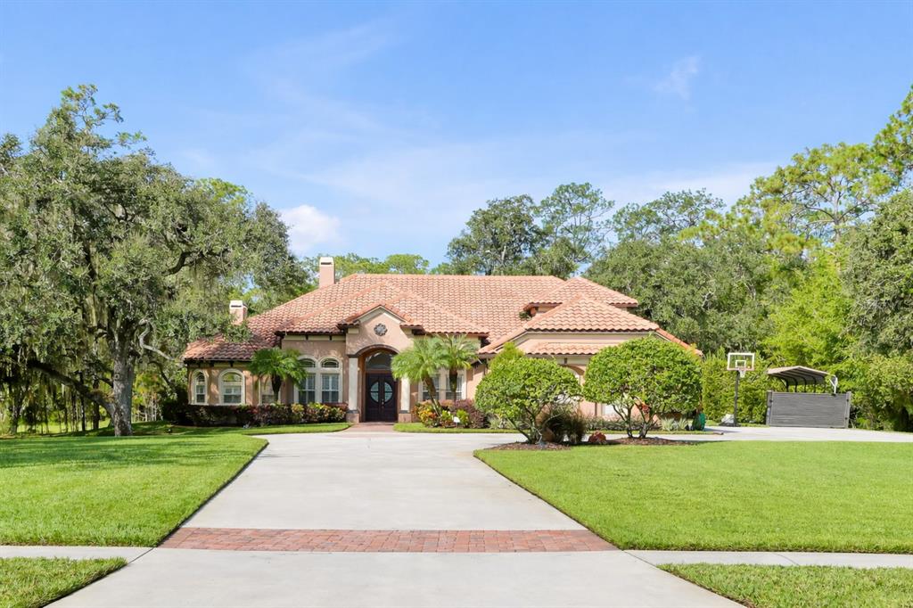 An aerial view shows a house with a tiled roof, a screened pool, and a driveway — 12012 RAMBLING OAK BOULEVARD, ORLANDO, FL
