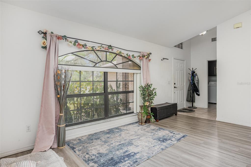 A living area features a large arched window, light wood flooring, and a patterned rug — 1356 CANARY DRIVE, DELAND, FL