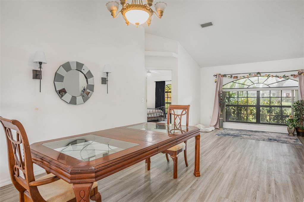 A dining room features a wooden table, a round mirror, and a large arched window — 1356 CANARY DRIVE, DELAND, FL