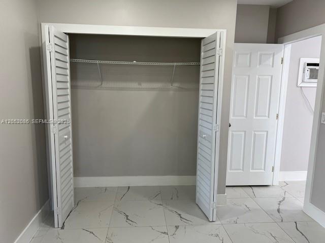 A closet with white louvered doors and a wire shelf sits on a marble-tiled floor — 922 NW 2nd St # 4, Miami FL 33128, MIAMI, FL