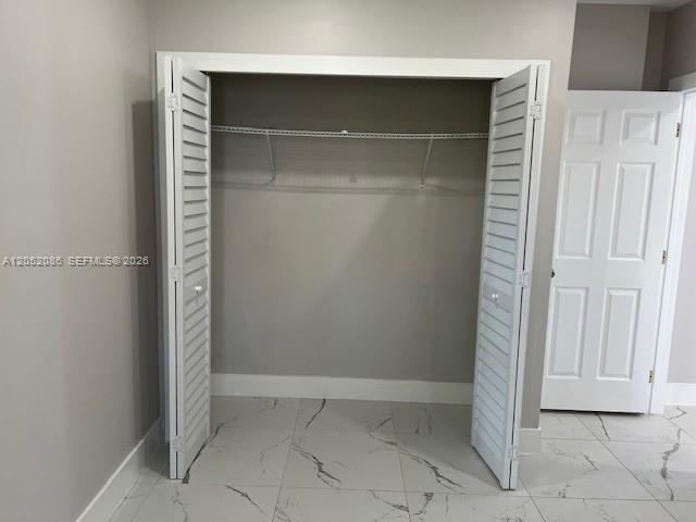 A closet with white louvered doors and a wire shelf above marble-patterned tile flooring — 922 NW 2nd St # 4, Miami FL 33128, MIAMI, FL
