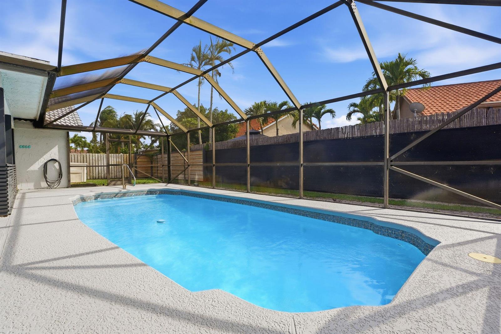 A rectangular swimming pool is enclosed by a metal-framed screen structure on a concrete patio — 9284 Laurel Green Drive, Boynton Beach FL 33437, BOYNTON BEACH, FL