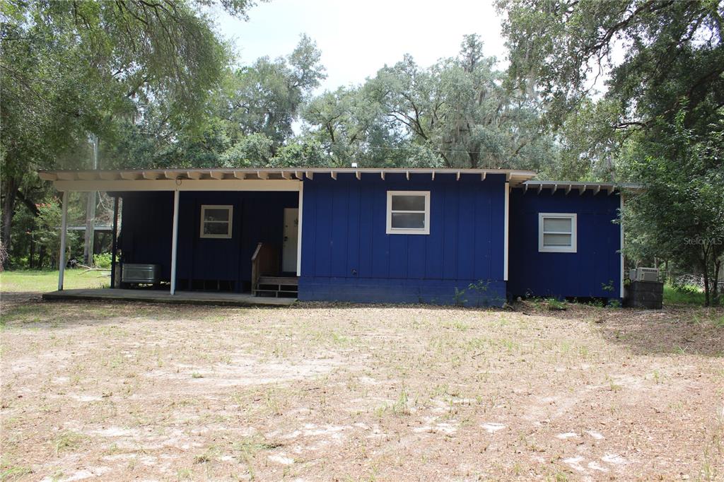 A blue, single-story house with a covered porch sits on a dirt lot among trees — 29160 SE 150TH STREET, ALTOONA, FL