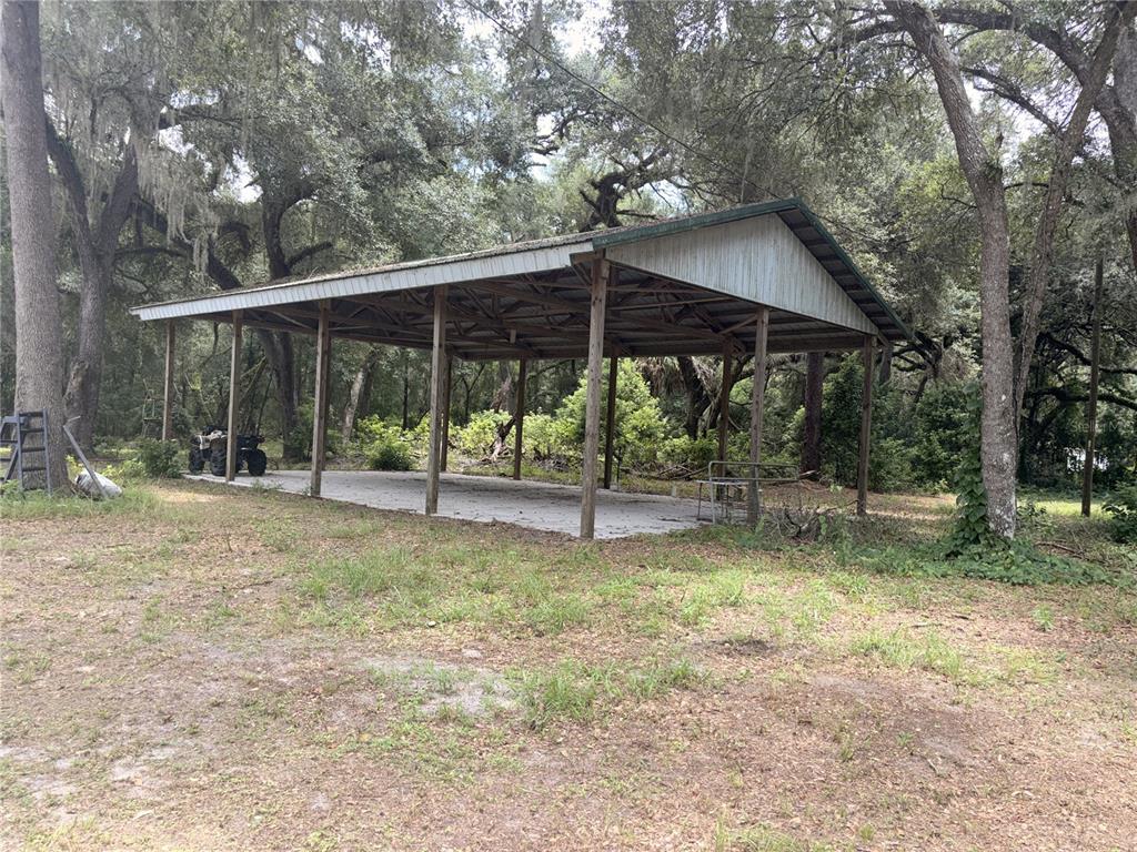 A large, open-sided metal pole barn with a concrete slab sits in a wooded area — 29160 SE 150TH STREET, ALTOONA, FL
