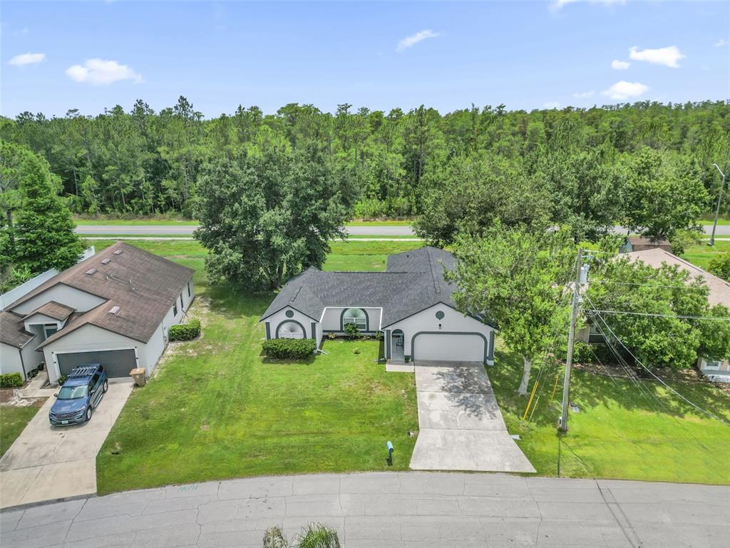 An aerial view shows two single-story suburban houses with driveways and lawns near a forest — 762 TOULON DRIVE, KISSIMMEE, FL