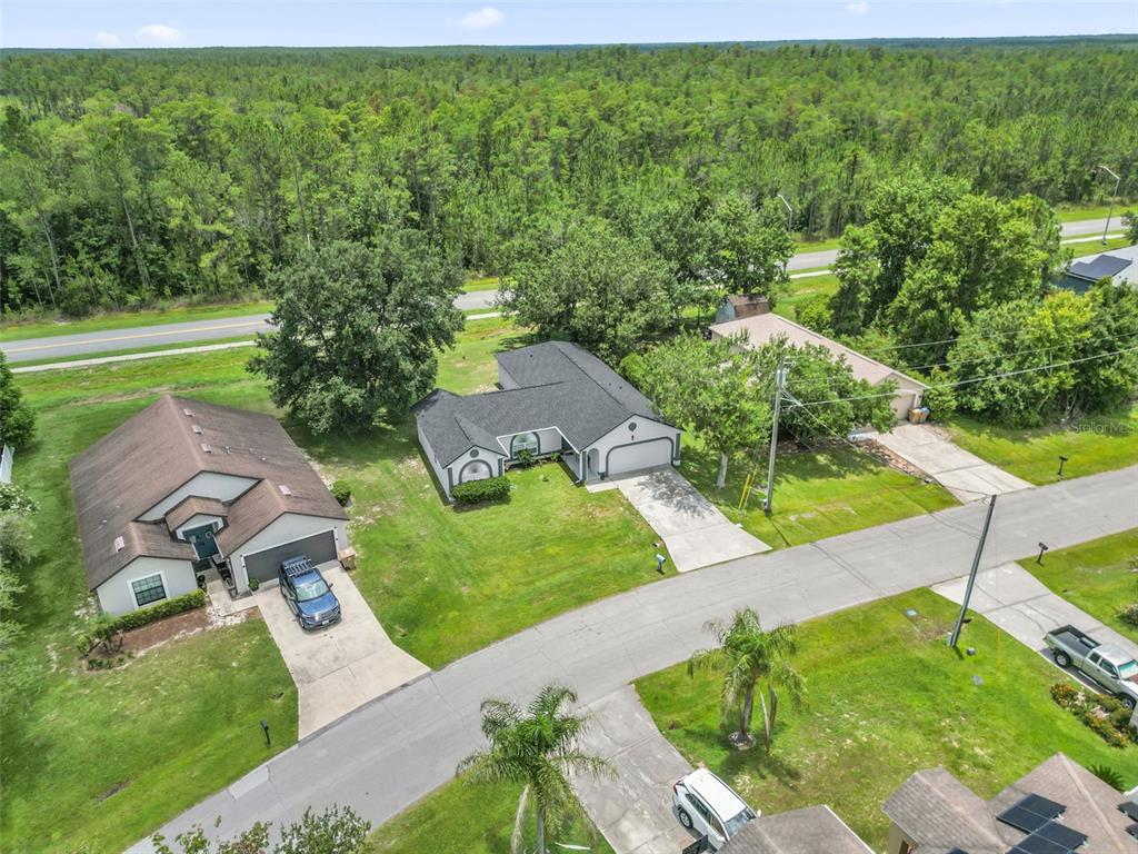 An aerial view shows two houses with driveways and lawns surrounded by a dense forest — 762 TOULON DRIVE, KISSIMMEE, FL