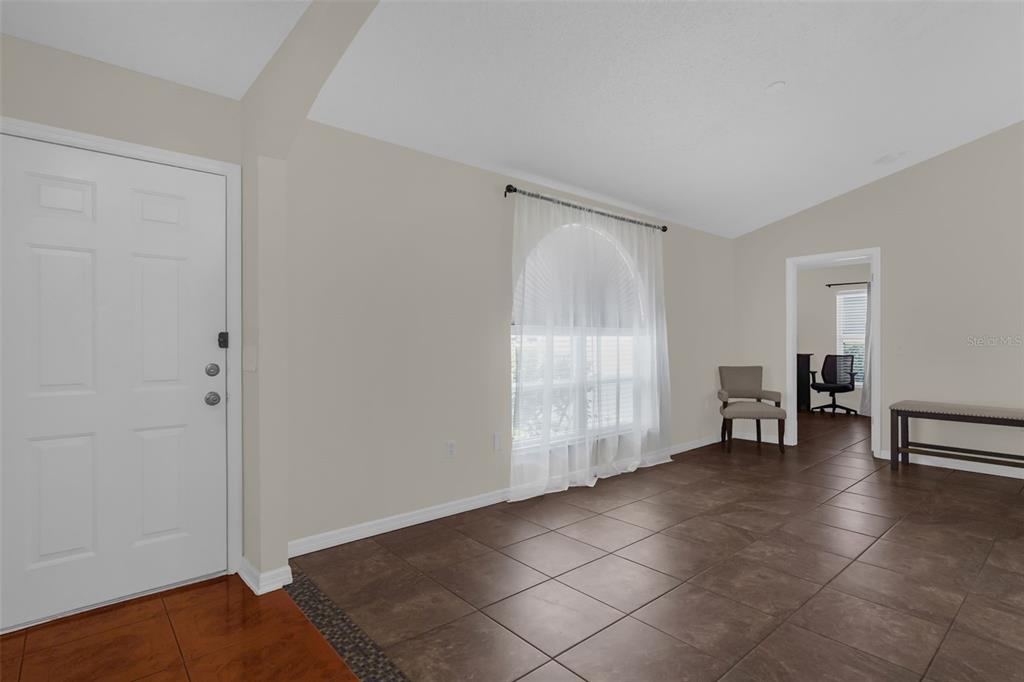 A room with tiled flooring, a white front door, and a large arched window — 762 TOULON DRIVE, KISSIMMEE, FL