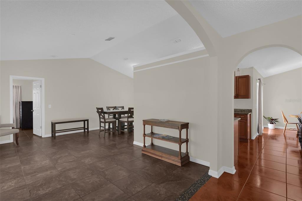 An open-concept living and dining area features tile flooring, neutral walls, and an arched entryway — 762 TOULON DRIVE, KISSIMMEE, FL