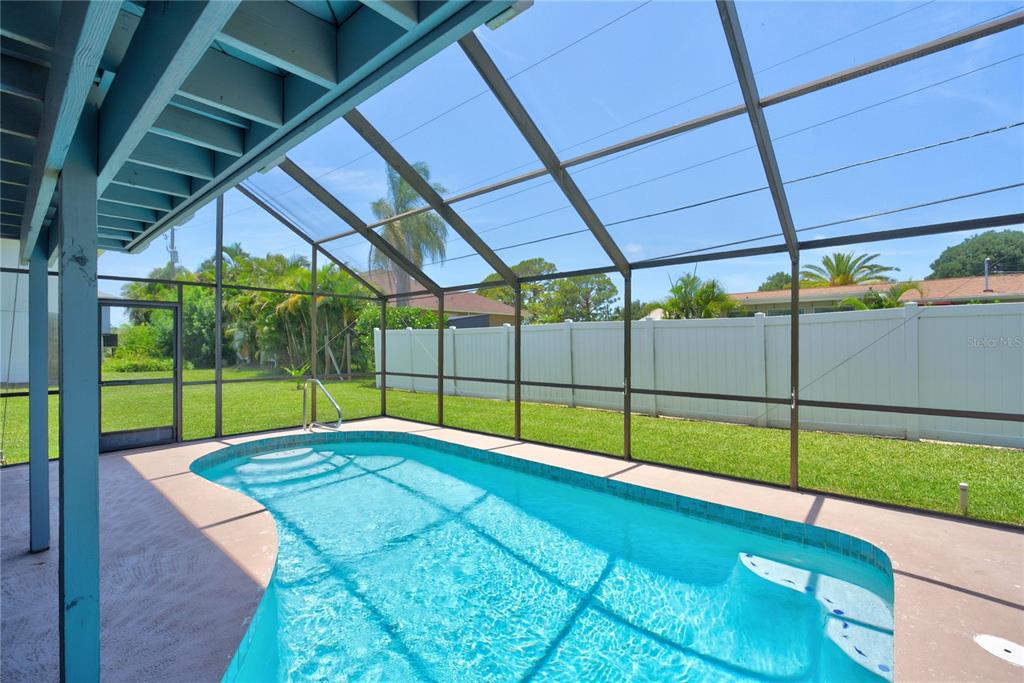 A screened-in swimming pool sits on a concrete patio in a fenced backyard — 1194 LINDEN ROAD, VENICE, FL