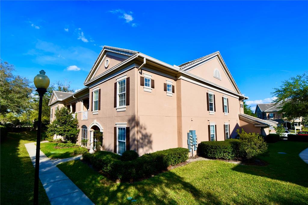 A two-story tan stucco apartment building with a gabled roof and surrounding landscaping — 14214 FREDRICKSBURG DRIVE UNIT 108, ORLANDO, FL