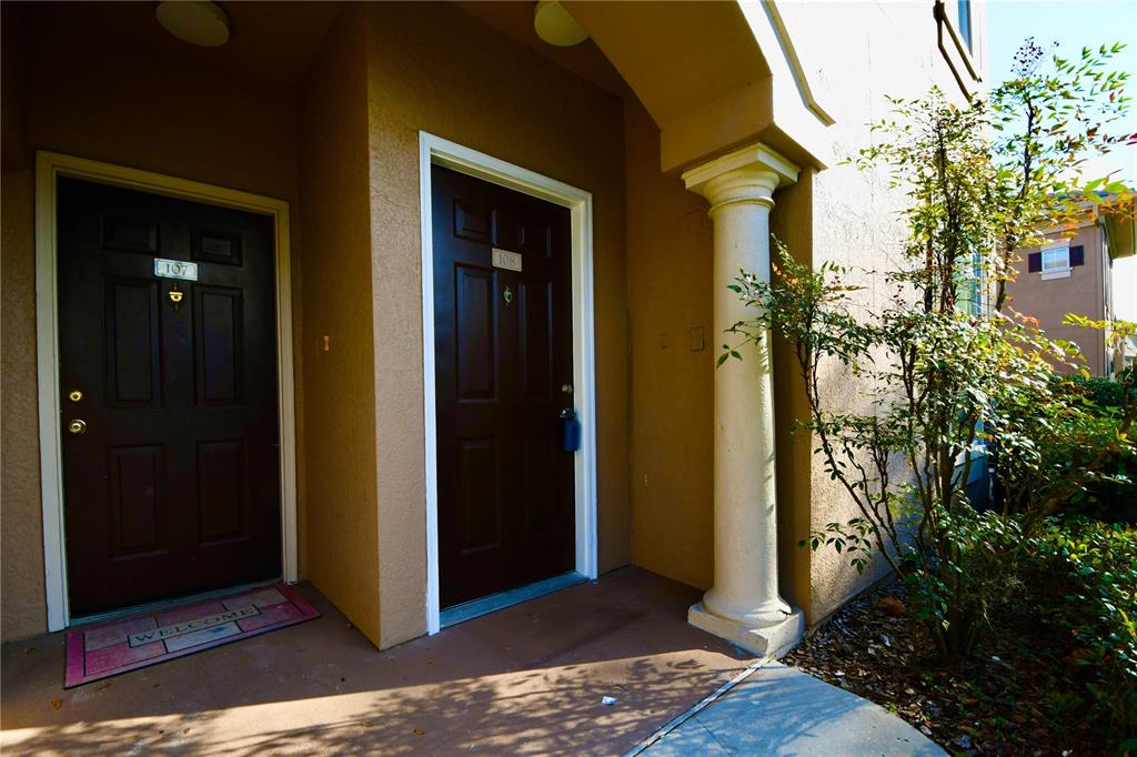Two dark brown apartment doors with unit numbers are set in a tan exterior wall — 14214 FREDRICKSBURG DRIVE UNIT 108, ORLANDO, FL