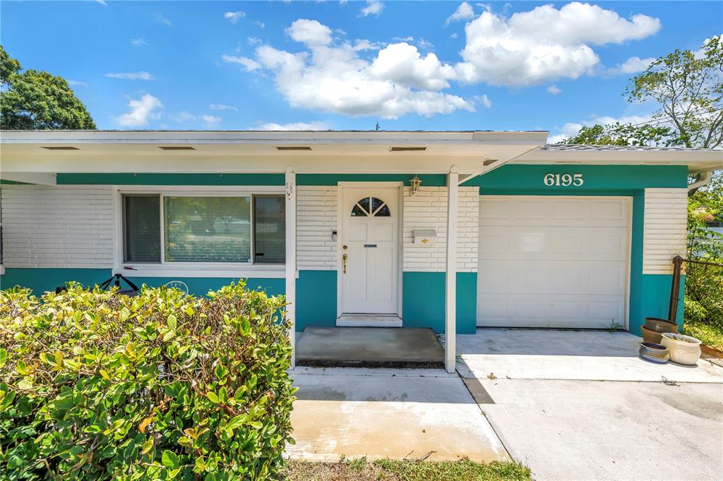 A single-story house features a teal and white exterior with a front door and garage — 6195 28TH AVENUE N, ST PETERSBURG, FL