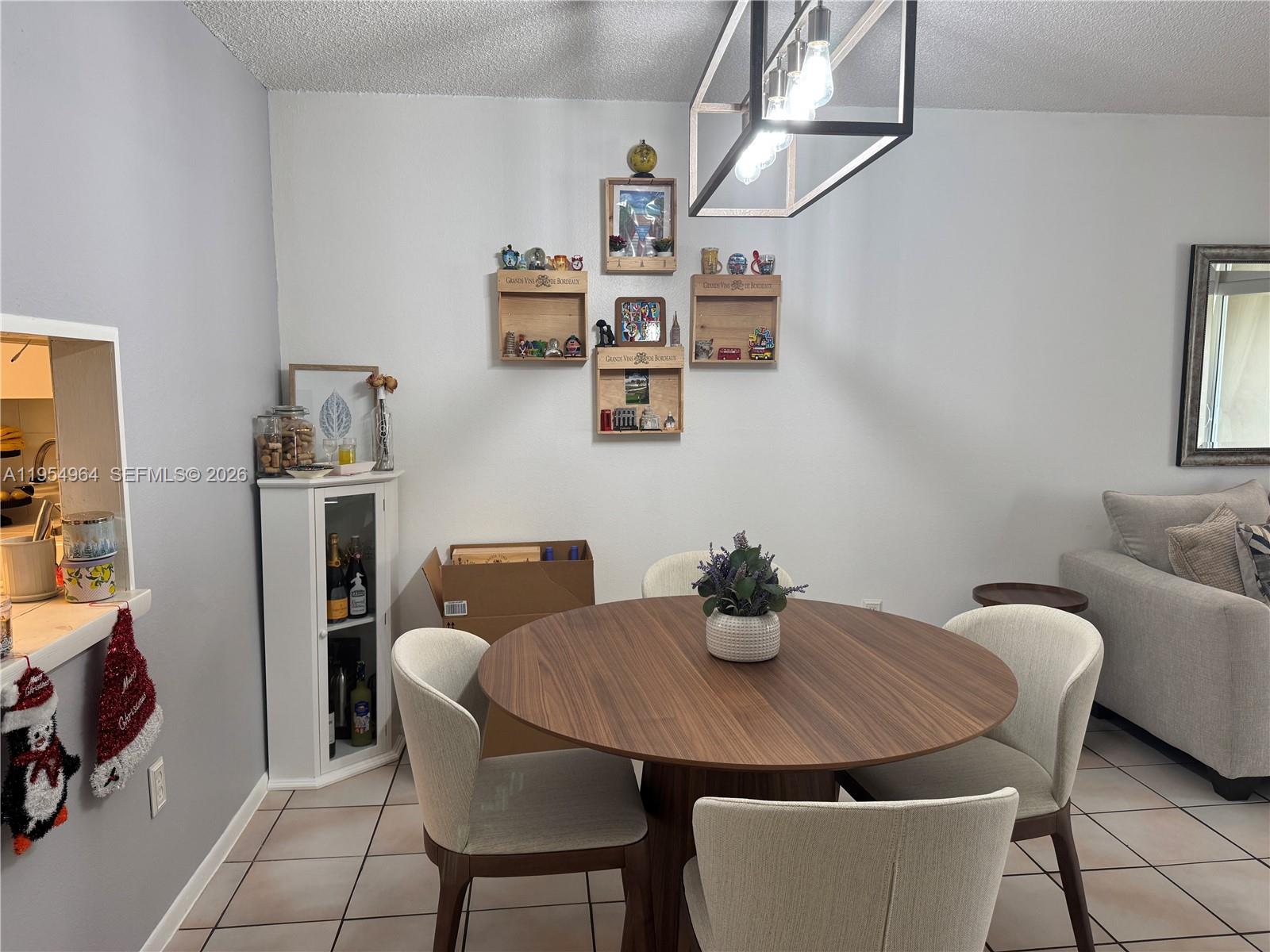 A dining area features a round wooden table, four upholstered chairs, and wall-mounted display crates — 7703 Camino Real # A106, Miami FL 33143, MIAMI, FL