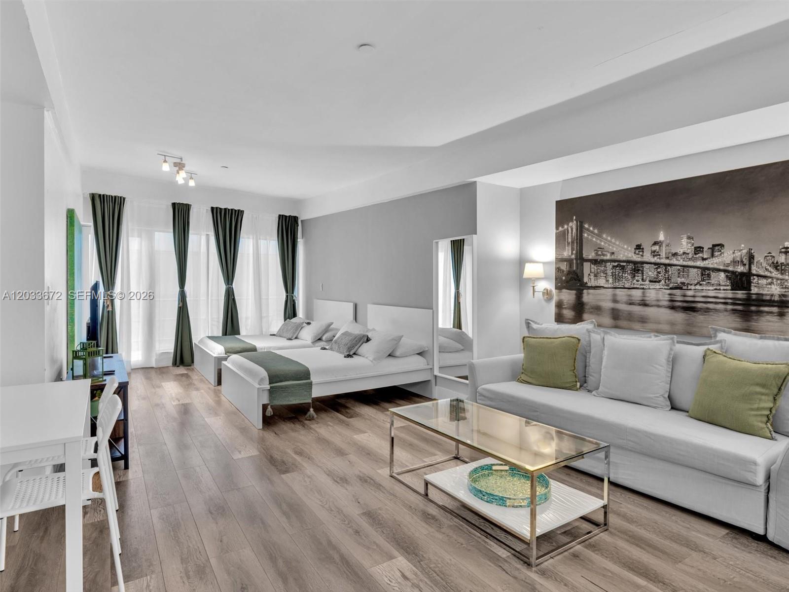 A studio apartment features two beds, a sofa, a coffee table, and wood-look flooring — 1052 Ocean Dr # C203, Miami Beach FL 33139, MIAMI BEACH, FL