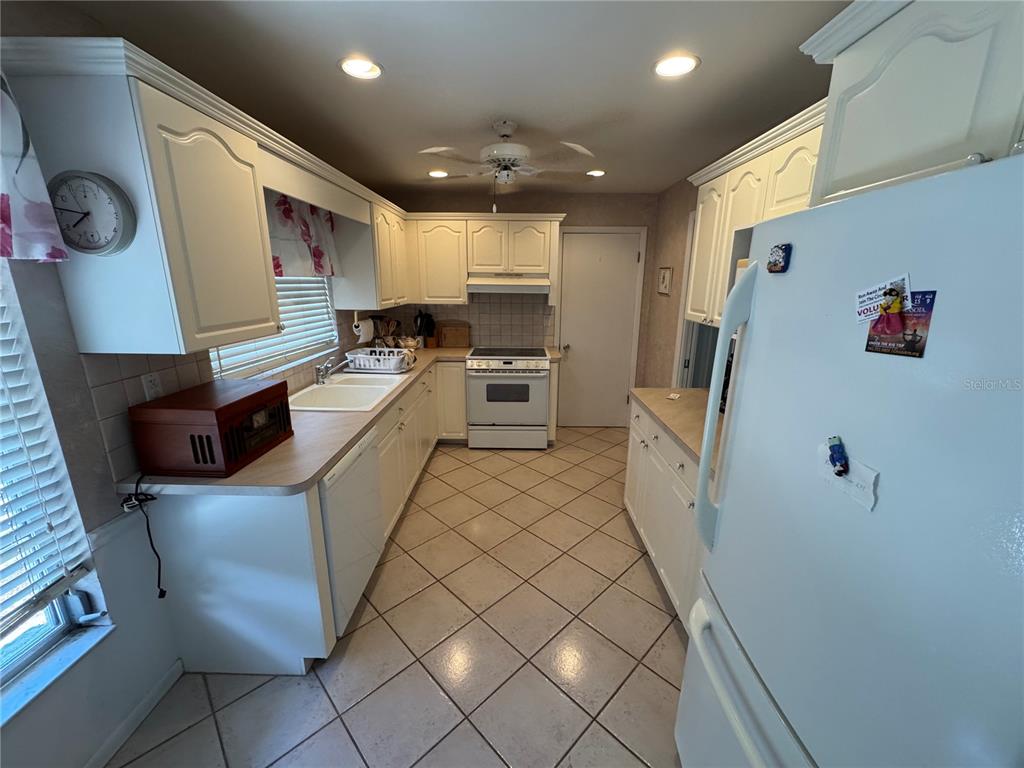 A kitchen with white cabinets, light countertops, tile flooring, and white appliances — 239 HAMMOCK TERRACE, VENICE, FL