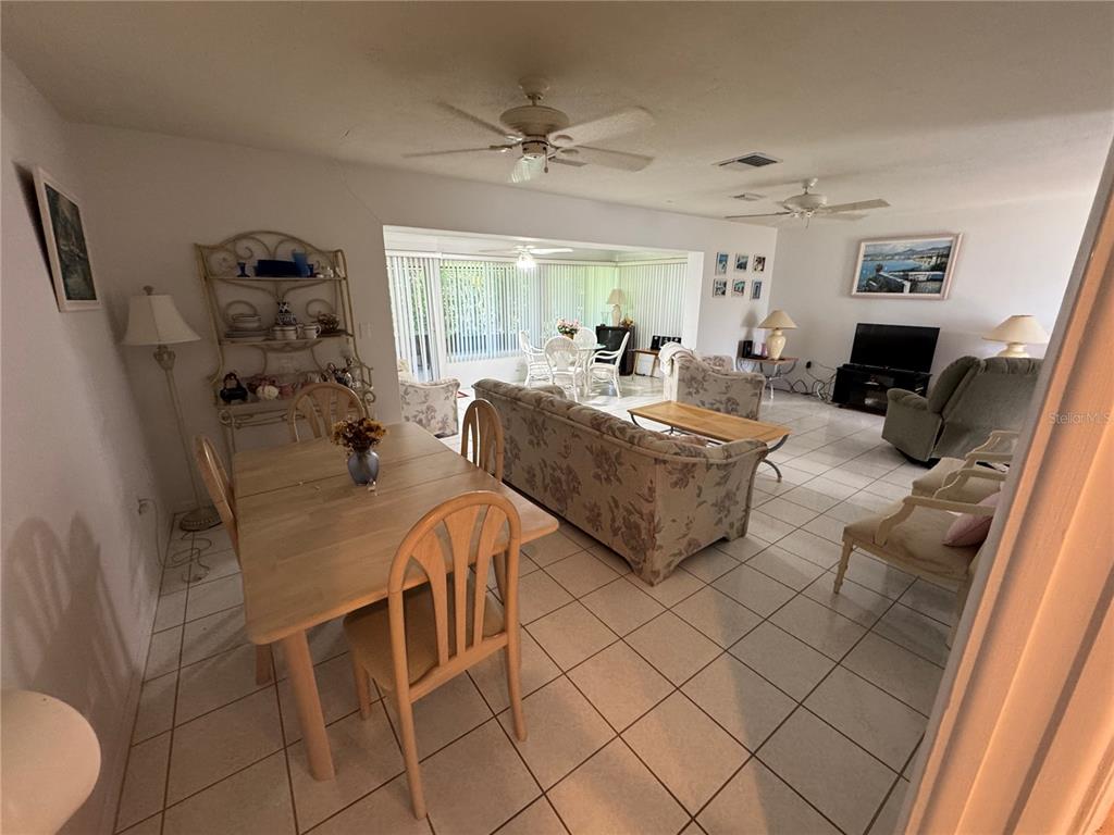 A dining area and living room with tile flooring, ceiling fans, and floral furniture — 239 HAMMOCK TERRACE, VENICE, FL