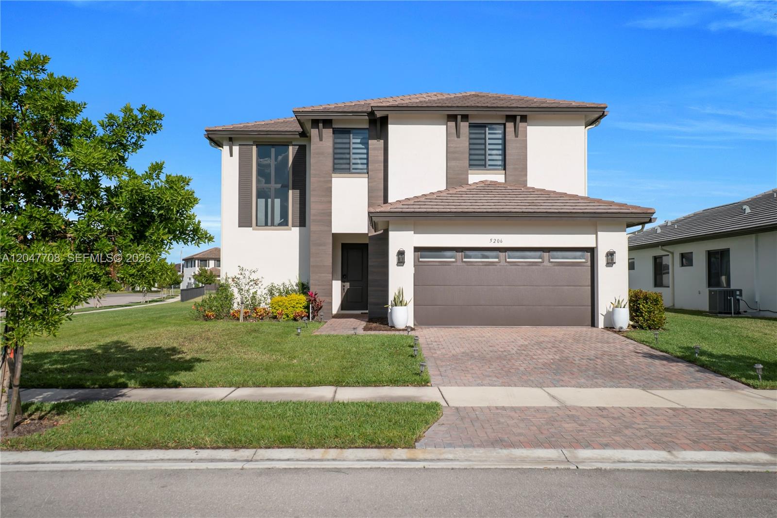 A two-story house features a brown garage, a paved driveway, and a landscaped front yard — 5206 Karlia Dr, Ave Maria FL 34142, AVE MARIA, FL