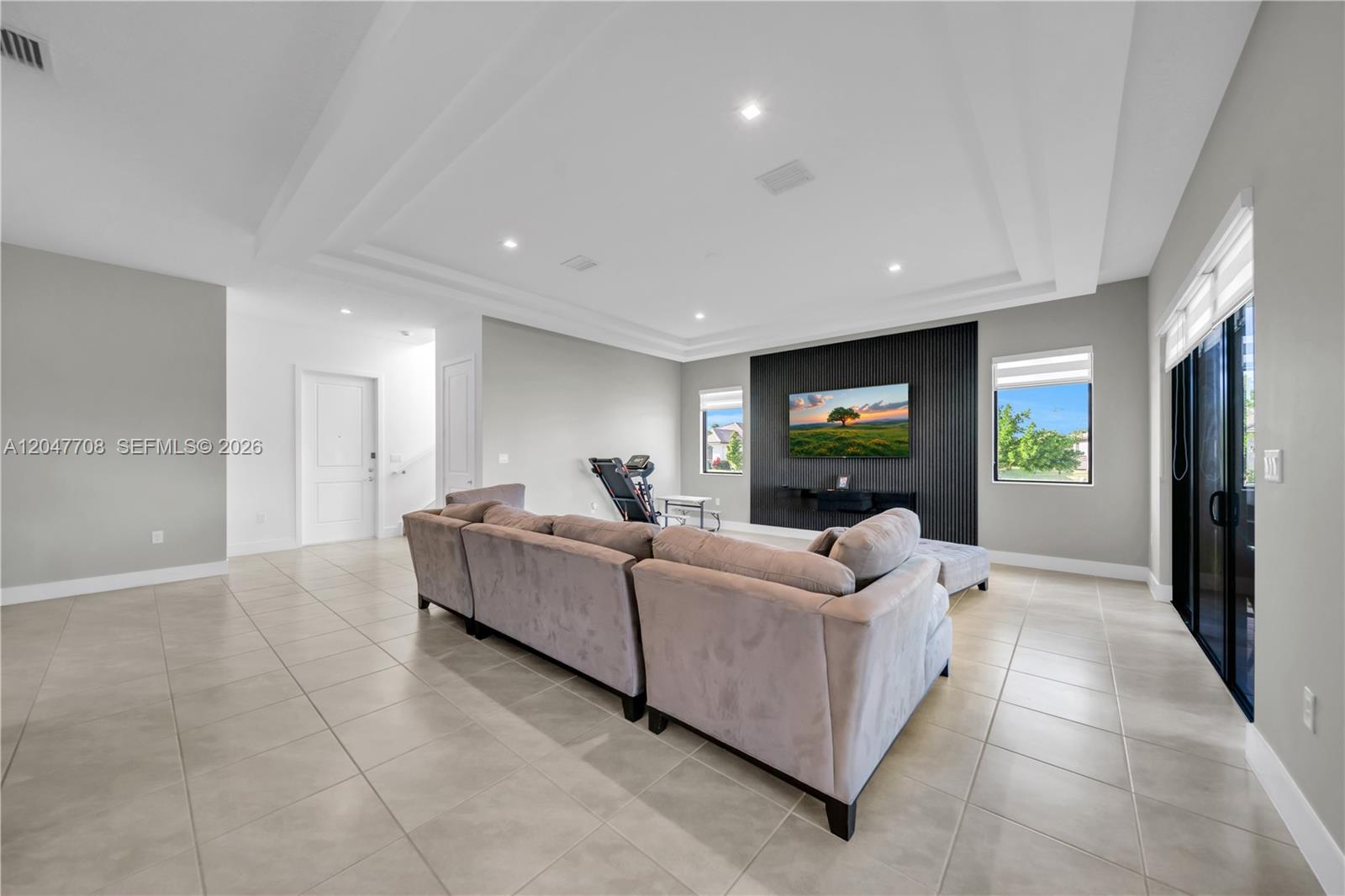 A living room features a large grey sectional sofa, tile floors, and a black slatted accent wall — 5206 Karlia Dr, Ave Maria FL 34142, AVE MARIA, FL