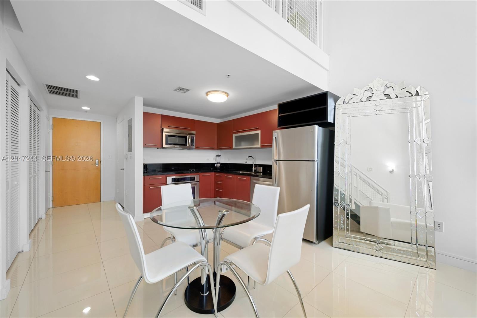 A kitchen with red cabinets, stainless steel appliances, and a glass dining table — 244 Biscayne Blvd # 451, Miami FL 33132, MIAMI, FL