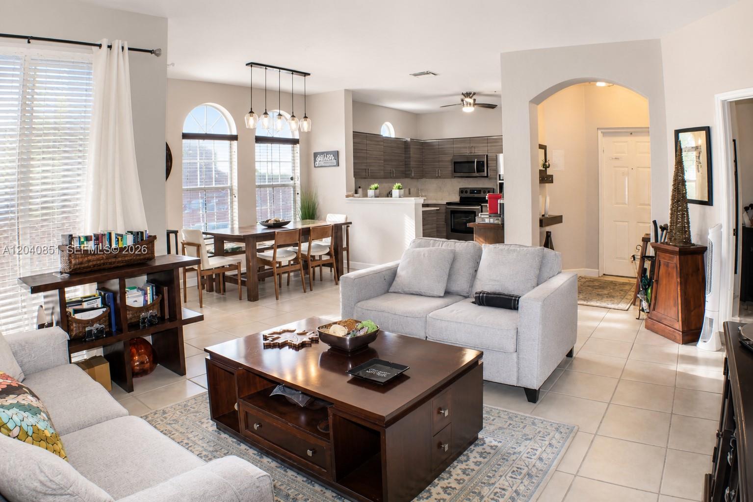 An open-concept living and dining area features tile flooring, neutral walls, and dark wood furniture — 4301 SW 160th Ave # 101, Miramar FL 33027, MIRAMAR, FL