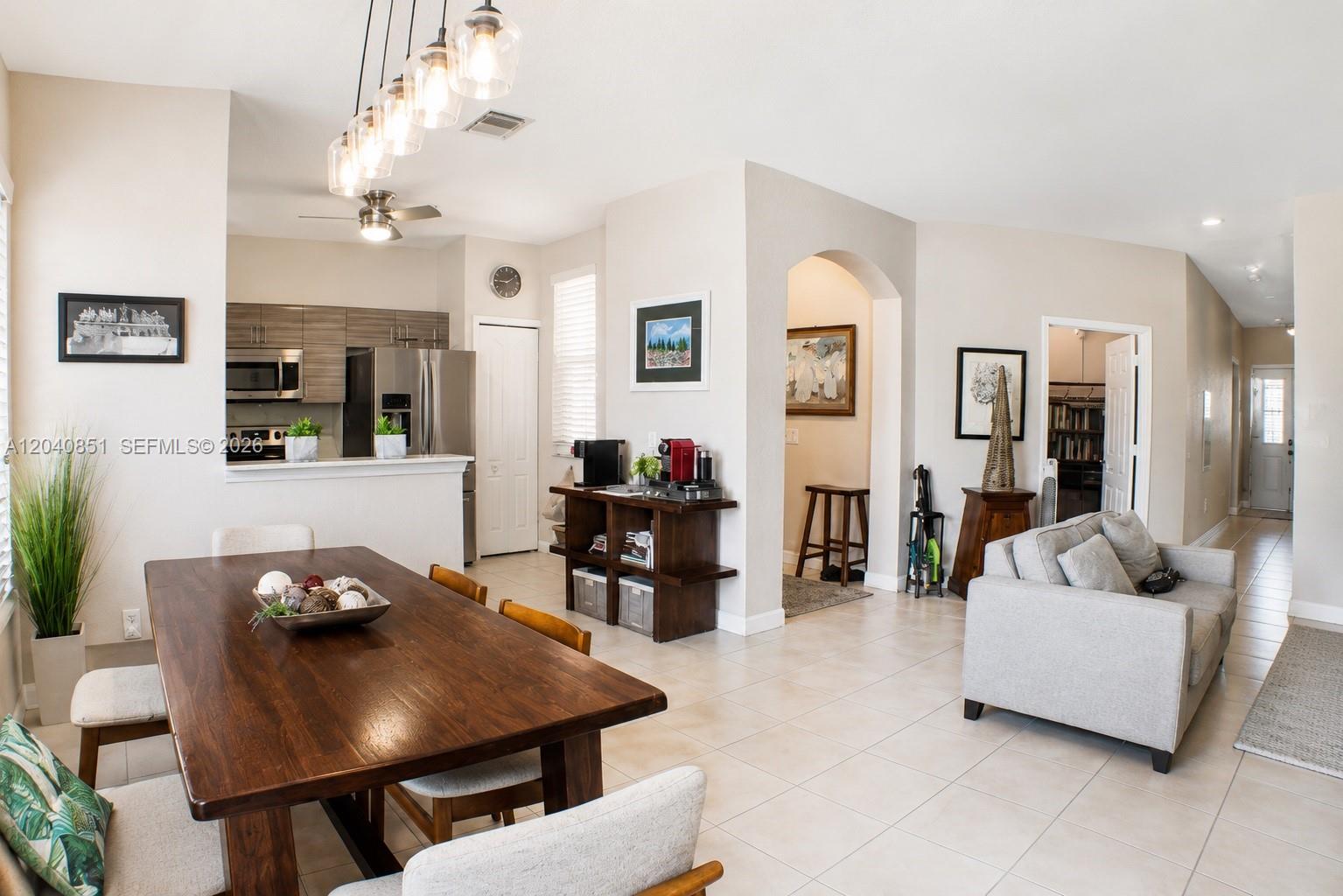 An open-concept dining and living area features a wooden table, tile flooring, and kitchen access — 4301 SW 160th Ave # 101, Miramar FL 33027, MIRAMAR, FL