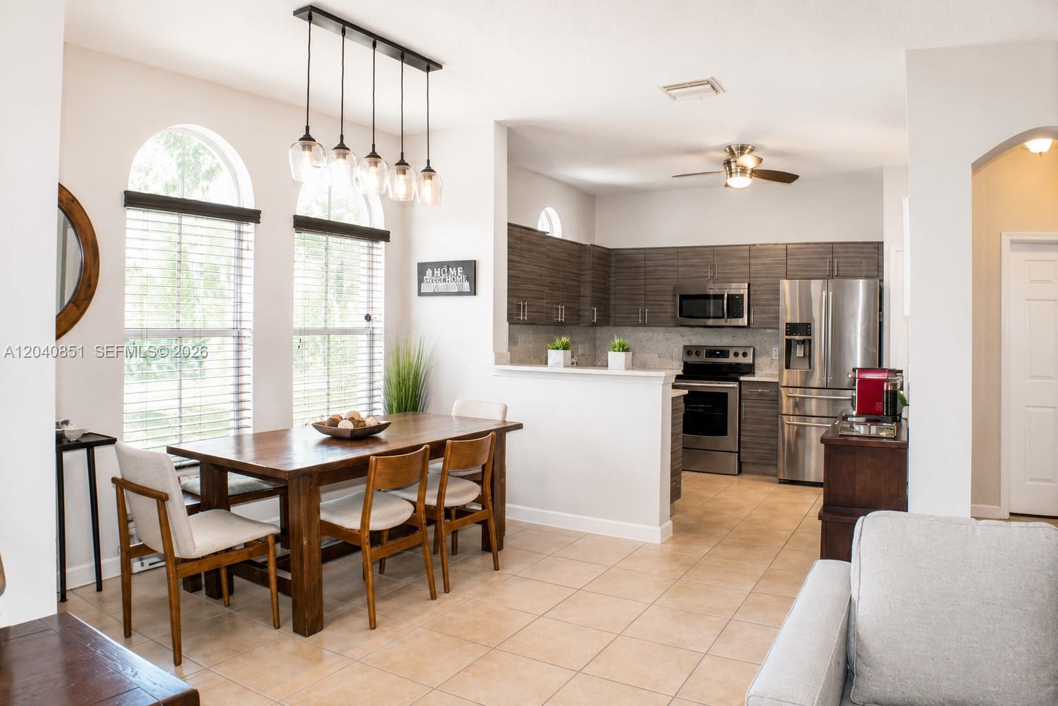 A dining area with a wooden table and chairs sits adjacent to a modern kitchen — 4301 SW 160th Ave # 101, Miramar FL 33027, MIRAMAR, FL