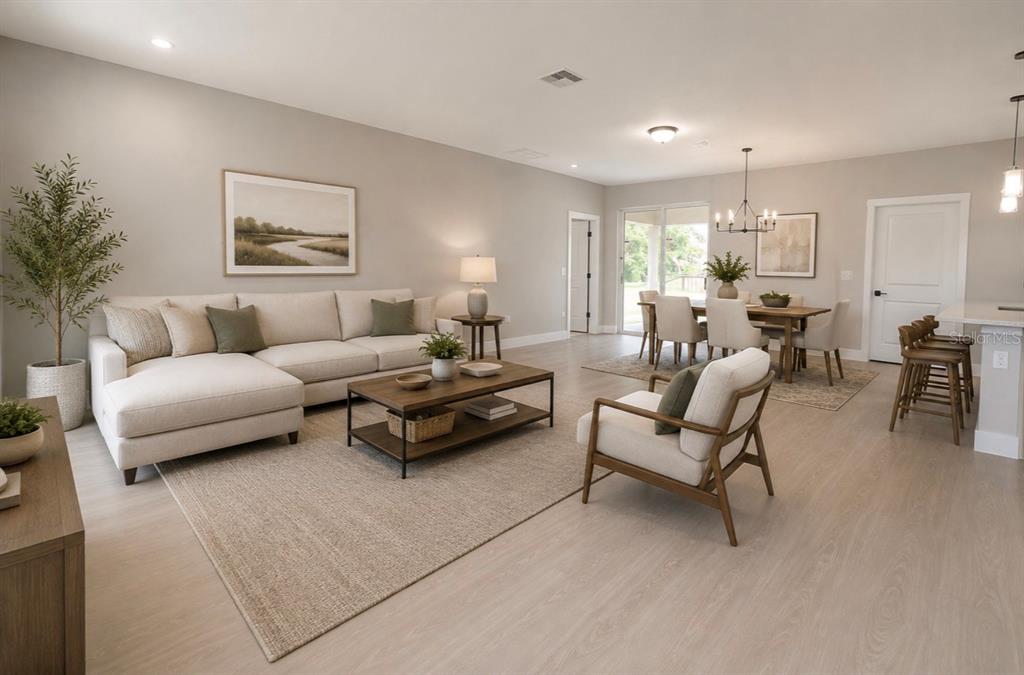 A bright, open-concept living and dining area features light wood flooring, neutral furniture, and recessed lighting — 701 FULMAR COURT, POINCIANA, FL