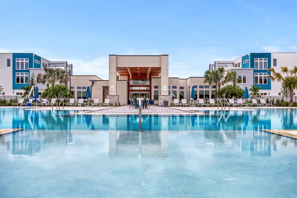A swimming pool sits in front of a modern apartment complex with a central clubhouse — 7917 NW SPECTRUM DRIVE, KISSIMMEE, FL