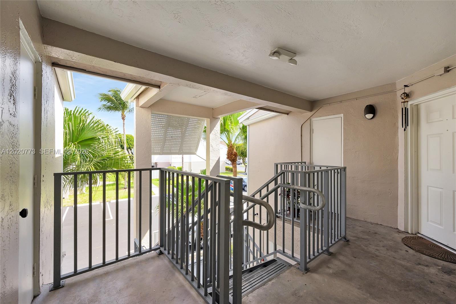 An outdoor covered landing features metal railings, stairs, and two white entry doors — 6720 NW 174th Ter # 18, Hialeah FL 33015, HIALEAH, FL