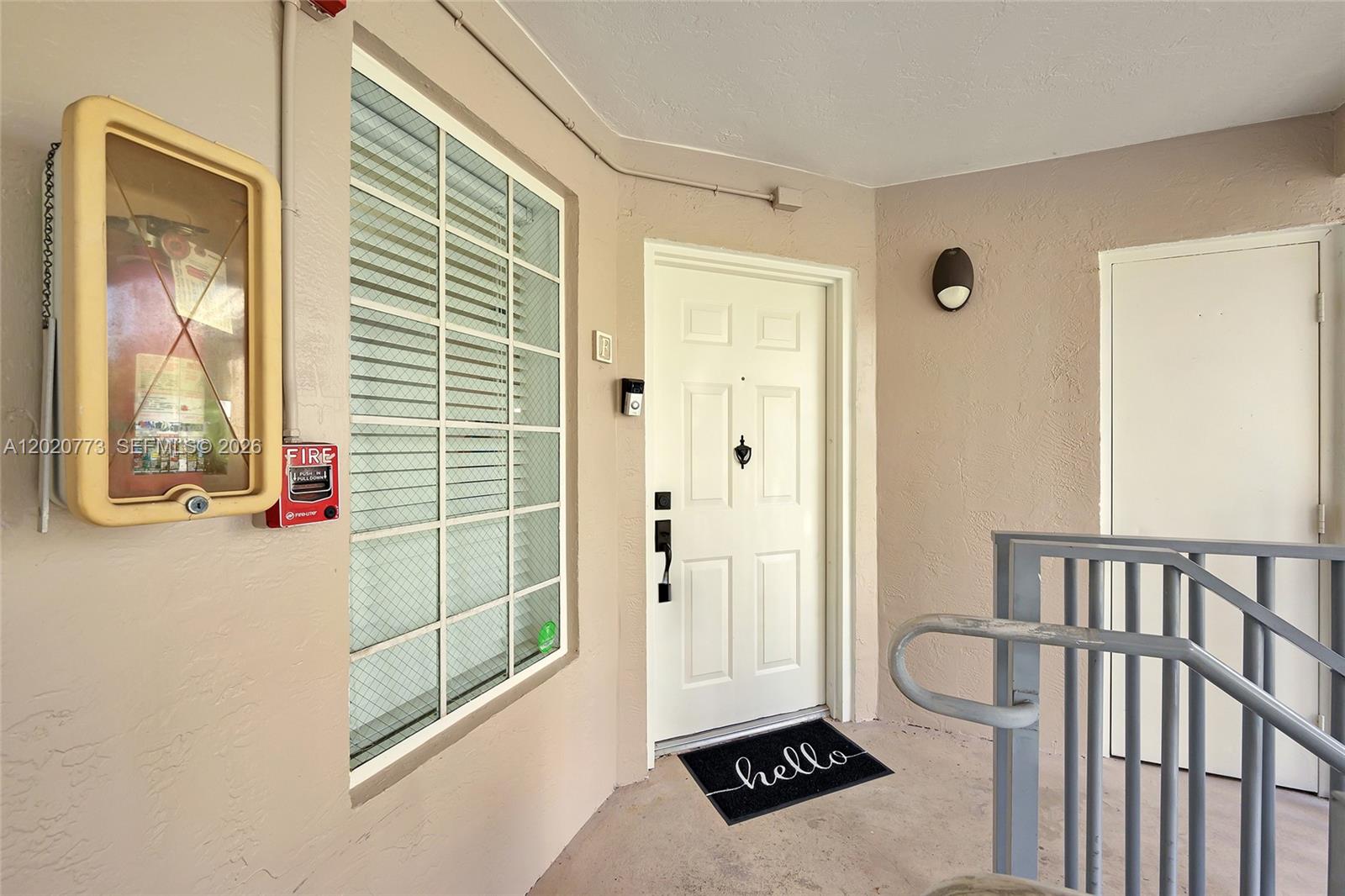 An exterior view of a building entrance featuring a white door and fire safety equipment — 6720 NW 174th Ter # 18, Hialeah FL 33015, HIALEAH, FL