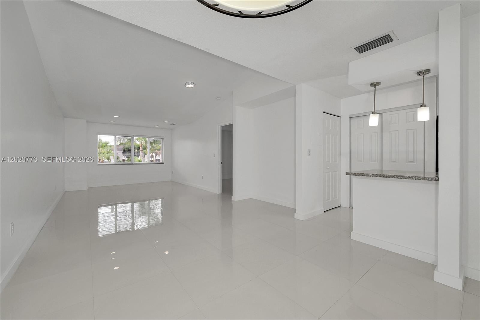 An empty room with white walls, glossy tile floors, and a breakfast bar with pendants — 6720 NW 174th Ter # 18, Hialeah FL 33015, HIALEAH, FL