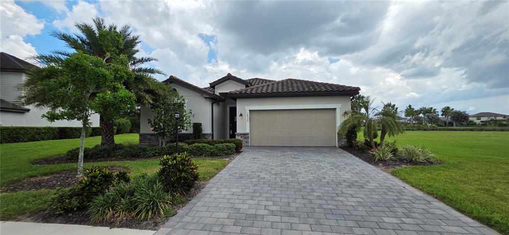 A single-story house with a tiled roof, beige stucco exterior, and a paved driveway — 16337 TRADEWIND TERRACE, BRADENTON, FL