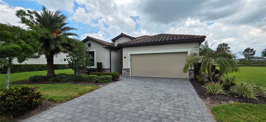 A single-story house with a beige garage, tile roof, and a paved driveway — 16337 TRADEWIND TERRACE, BRADENTON, FL