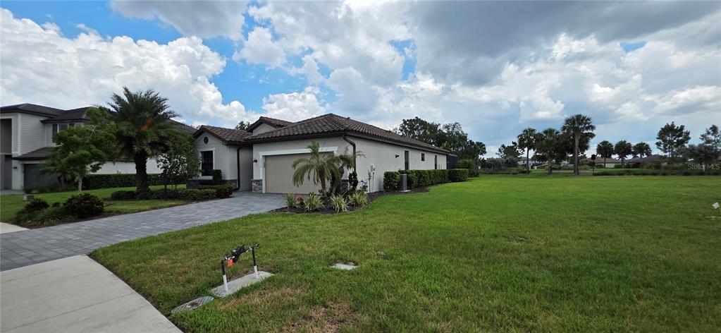 A single-story house with a tiled roof, two-car garage, and a large side yard — 16337 TRADEWIND TERRACE, BRADENTON, FL
