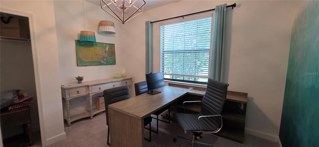A home office features a wooden desk, black chairs, a console table, and a window — 16337 TRADEWIND TERRACE, BRADENTON, FL