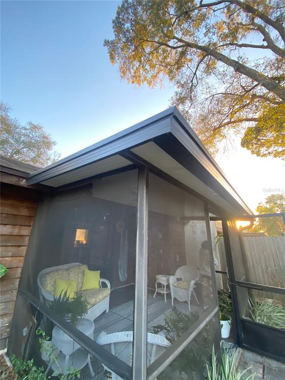 A screened-in porch with white wicker furniture and a dark metal roof overhang — 505 BRISTOL DRIVE, ALTAMONTE SPRINGS, FL