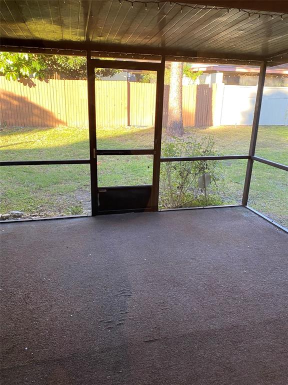 A screened-in porch with a carpeted floor and a door leading to a grassy backyard — 505 BRISTOL DRIVE, ALTAMONTE SPRINGS, FL