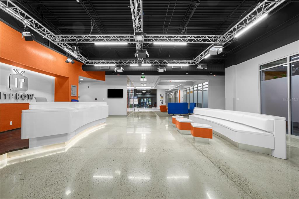 A modern office lobby features a white reception desk, polished concrete floors, and industrial lighting — 7525 NW 4TH BOULEVARD, GAINESVILLE, FL