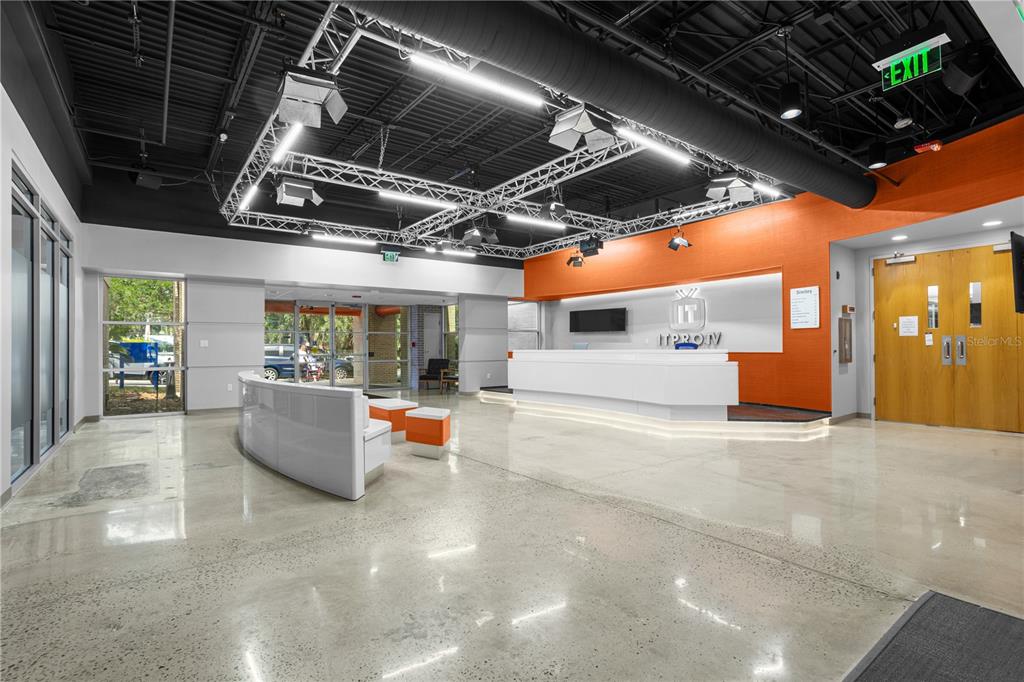 A modern office lobby features a white reception desk, polished concrete floors, and industrial lighting — 7525 NW 4TH BOULEVARD, GAINESVILLE, FL