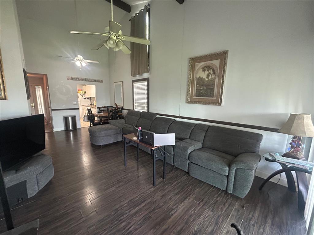 A living room with dark wood floors, a large sectional sofa, and high vaulted ceilings — 6519 W NEWBERRY ROAD UNIT 309, GAINESVILLE, FL