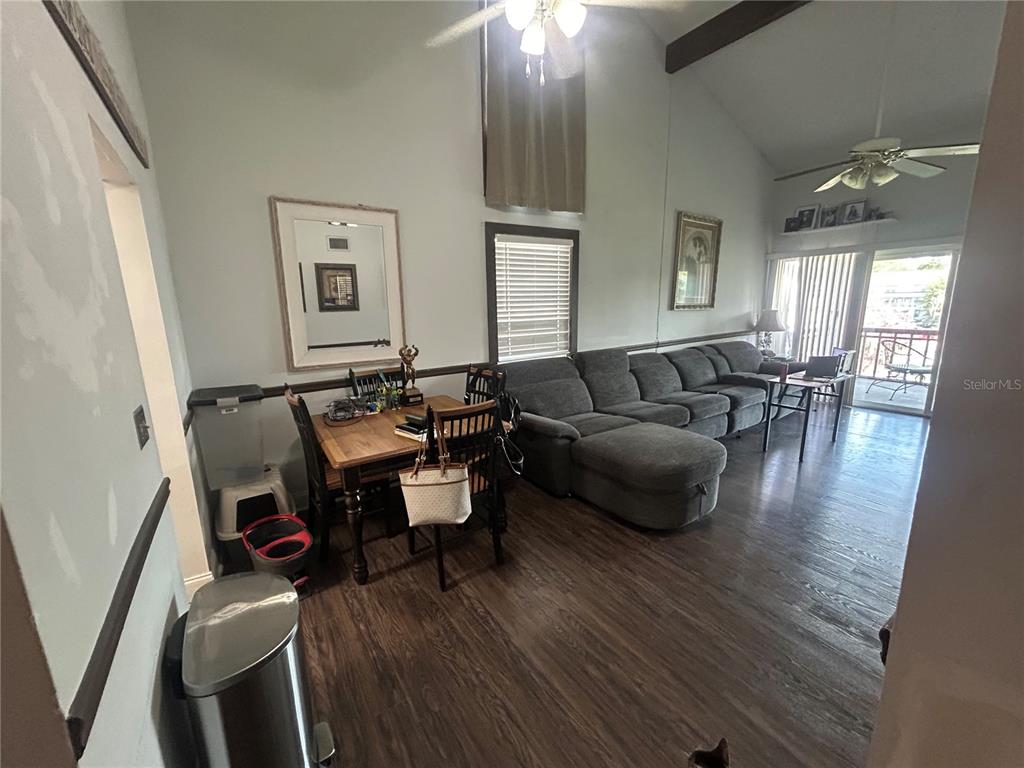 A living room with a gray sectional sofa, a dining table, and vaulted ceilings — 6519 W NEWBERRY ROAD UNIT 309, GAINESVILLE, FL