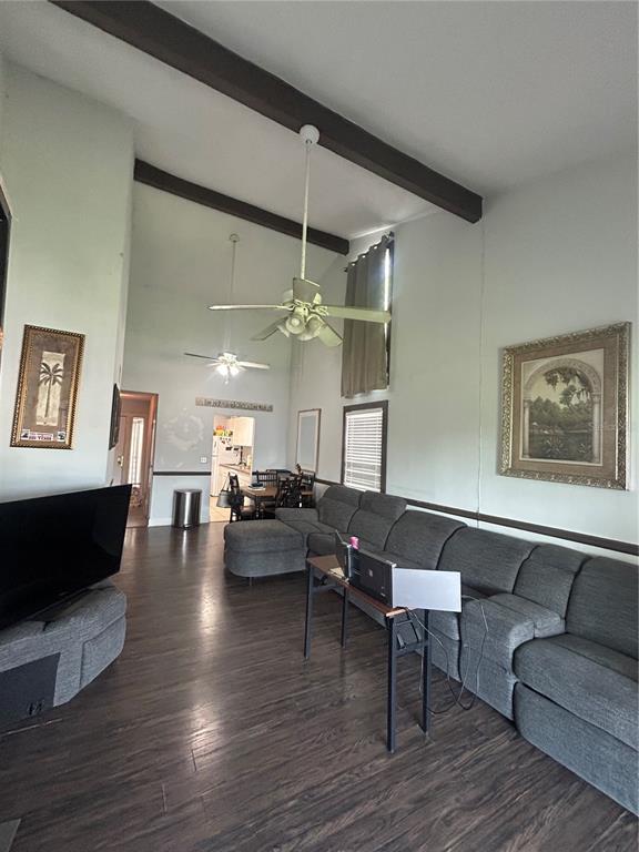 A living room features vaulted ceilings with exposed beams, dark wood flooring, and a sectional sofa — 6519 W NEWBERRY ROAD UNIT 309, GAINESVILLE, FL
