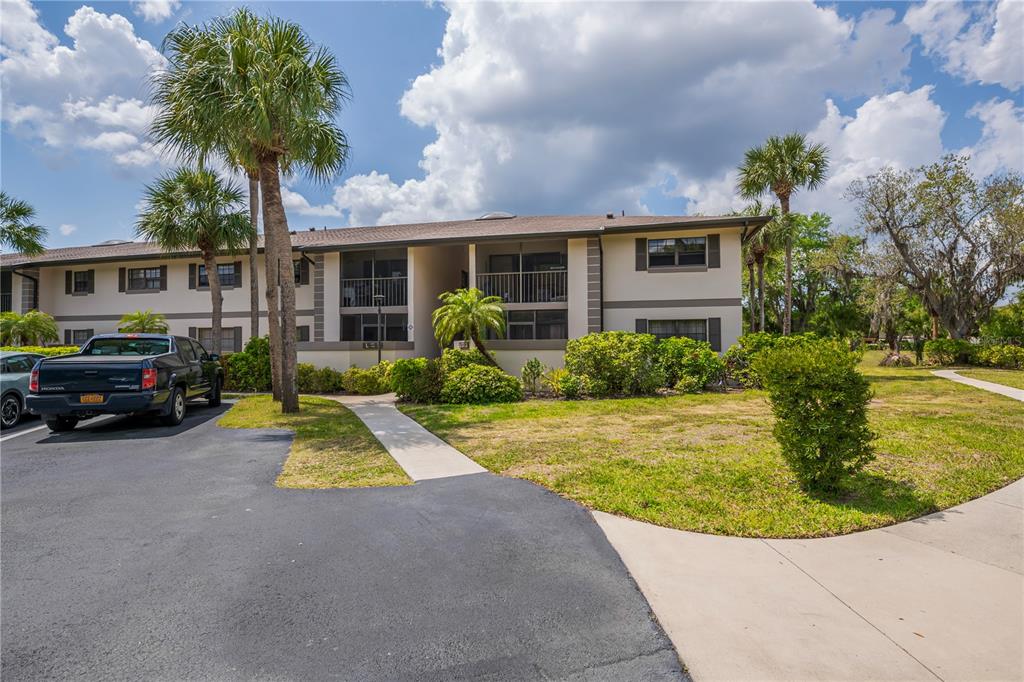 A two-story apartment building with a parking lot and palm trees in front — 1515 FORREST NELSON BOULEVARD UNIT L105, PORT CHARLOTTE, FL