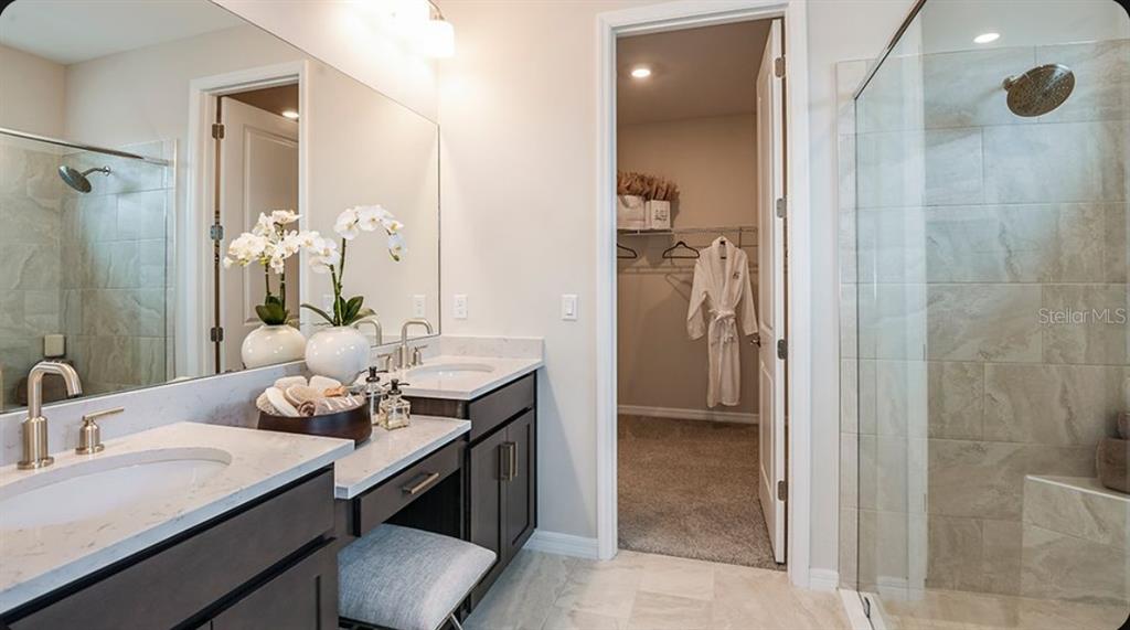 A bathroom features a glass-enclosed shower, a white vanity with a mirror, and tile flooring — 7028 FOXBORO WAY, NOKOMIS, FL