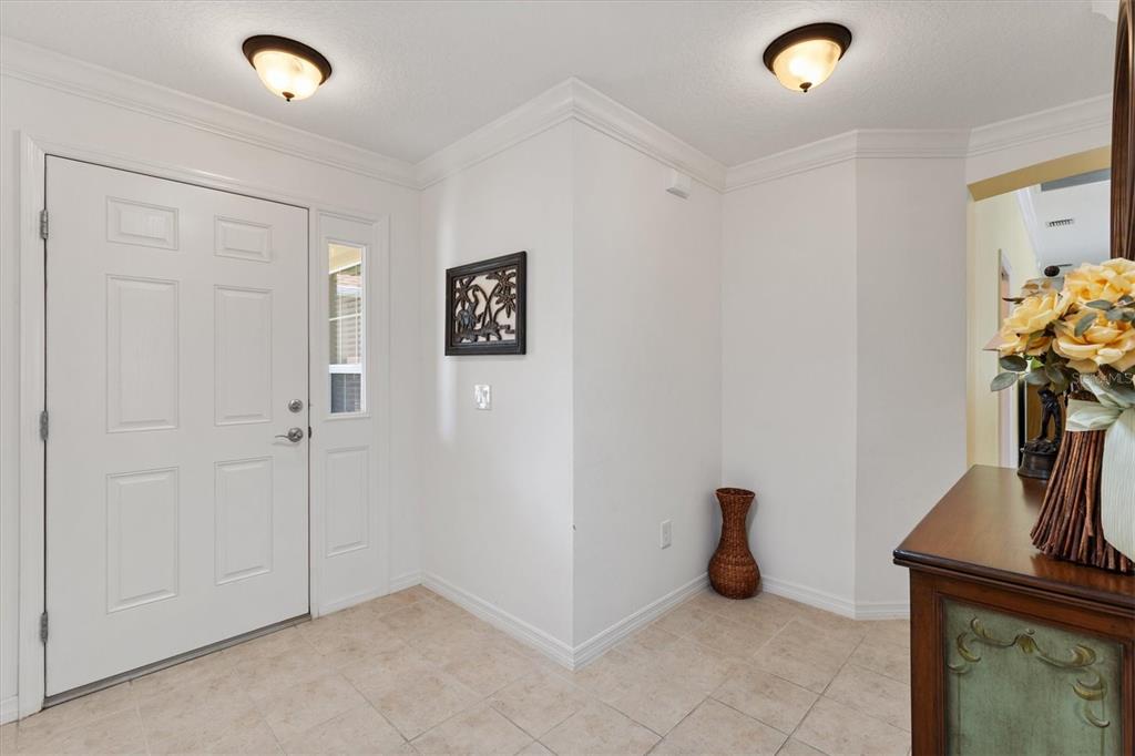 A bright entryway features white walls, tile flooring, two ceiling lights, and a front door — 3025 BARTOW LANE, THE VILLAGES, FL