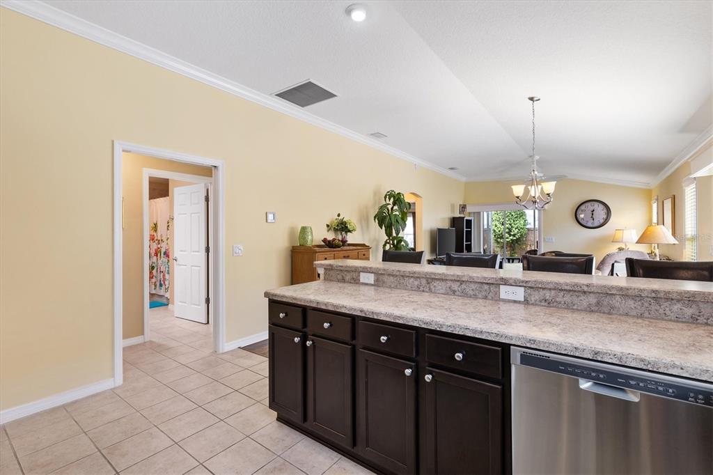 A kitchen island with dark cabinets and granite countertops overlooks an open-concept living area — 3025 BARTOW LANE, THE VILLAGES, FL