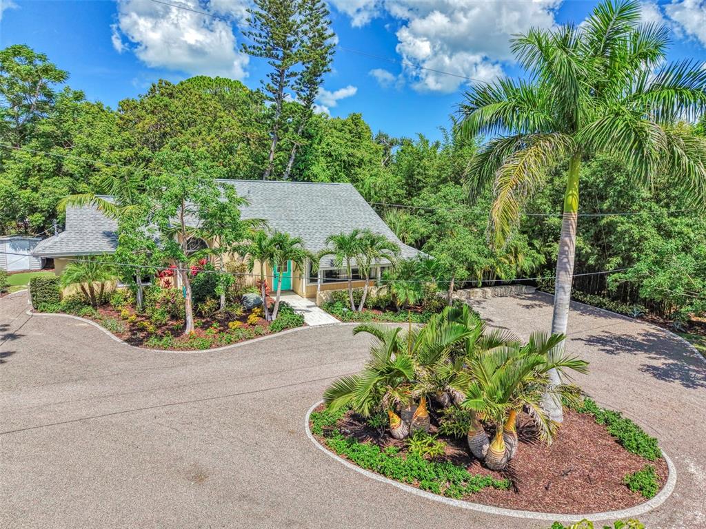 A house with a circular driveway and palm trees sits in a lush, wooded area — 2137 WORRINGTON STREET, SARASOTA, FL