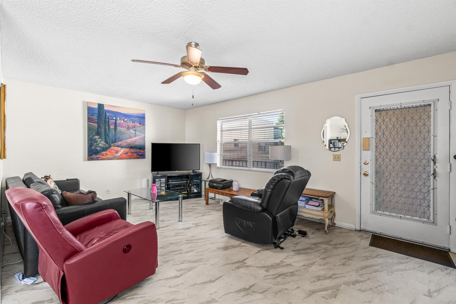 A living room features a ceiling fan, tiled floors, a red recliner, and a front door — 184 Flanders D, Delray Beach FL 33484, DELRAY BEACH, FL